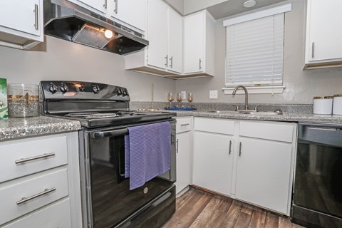 A kitchen with a black oven and white cabinets in our model at The Oasis apartments in Bossier City, LA